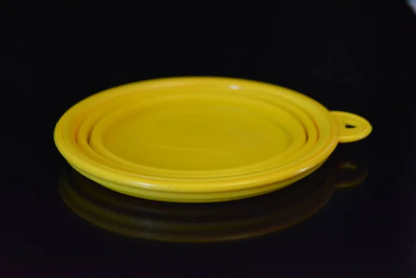 Sarı katlama ve çok fonksiyonlu kauçuk plaka, siyah parlak yüzey üzerinde plastik kenarlı bir kase.