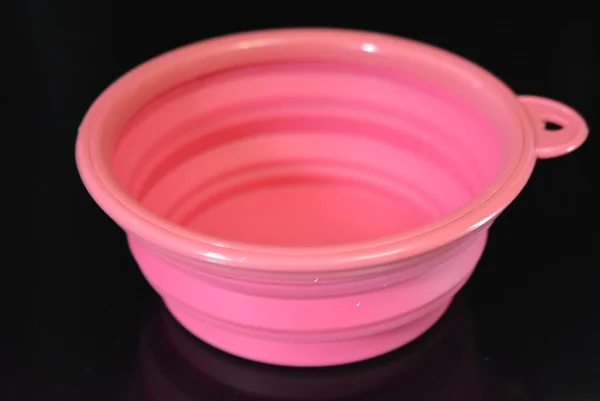 粉红色折叠和多功能橡胶板 黑色光泽表面上带有塑料边缘的碗 — 图库照片