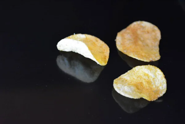 Deliciosos Batatas Fritas Crocantes Embalagem Encontram Uma Superfície Brilhante Preto — Fotografia de Stock