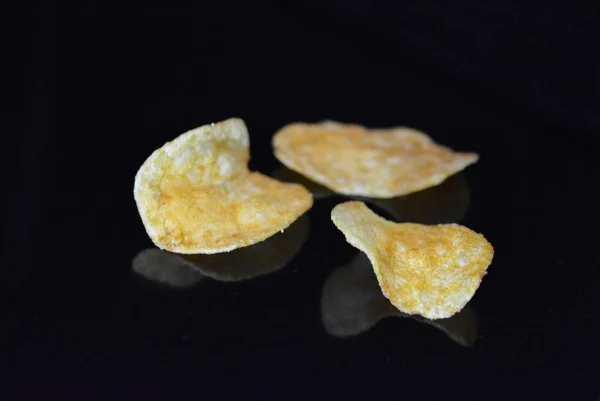 Pyszne Chrupiące Chipsy Ziemniaczane Opakowania Leżą Czarnej Błyszczącej Powierzchni Refleksją — Zdjęcie stockowe