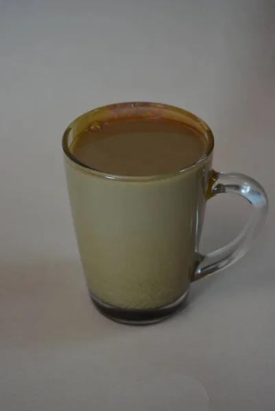 Tasty, home-made coffee with milk in a glass cup on a gray background.