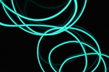 Geceleri parlayan turkuaz renkli malzemeden yapılmış sıradışı parlak teller. Kaotik gökyüzü mavitelleri, ışık kılavuzu elektrolüminesans telleri, elektrolüminesans parlak siyah bir yüzey üzerinde yer alır.