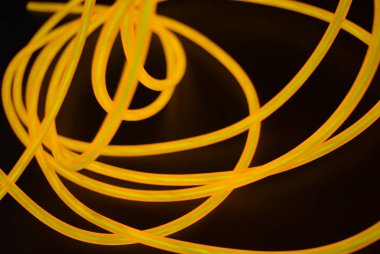 Parlak turuncu parlak tel, bükülmüş ışık teli, kablo. Farklı bükümler, sulu el tel ile lectroluminesans tellerin farklı şekil ve görüntüleri.