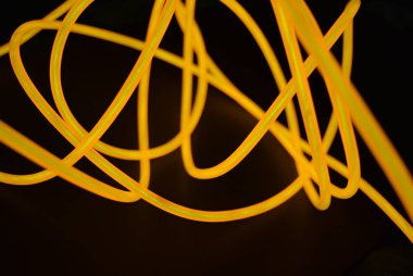 Parlak turuncu parlak tel, bükülmüş ışık teli, kablo. Farklı bükümler, sulu el tel ile lectroluminesans tellerin farklı şekil ve görüntüleri.