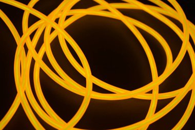 Parlak turuncu parlak tel, bükülmüş ışık teli, kablo. Farklı bükümler, sulu el tel ile lectroluminesans tellerin farklı şekil ve görüntüleri.