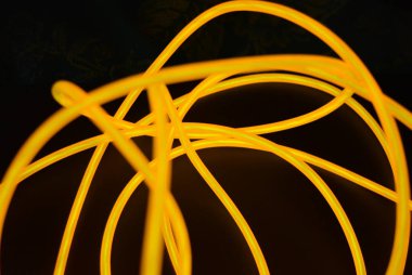 Parlak turuncu parlak tel, bükülmüş ışık teli, kablo. Farklı bükümler, sulu el tel ile lectroluminesans tellerin farklı şekil ve görüntüleri.