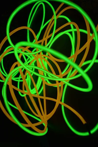 Bright luminous yellow and green, lime neon wires in different formats and layouts. An electroluminescent wire, a neon light guide, an ice tube are folded into different structures and shapes.