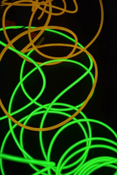 Bright luminous yellow and green, lime neon wires in different formats and layouts. An electroluminescent wire, a neon light guide, an ice tube are folded into different structures and shapes.