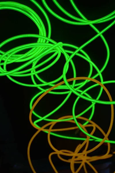 Bright luminous yellow and green, lime neon wires in different formats and layouts. An electroluminescent wire, a neon light guide, an ice tube are folded into different structures and shapes.