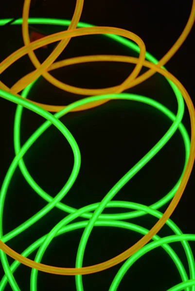 Bright luminous yellow and green, lime neon wires in different formats and layouts. An electroluminescent wire, a neon light guide, an ice tube are folded into different structures and shapes.