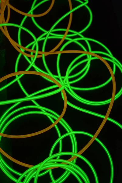 Bright luminous yellow and green, lime neon wires in different formats and layouts. An electroluminescent wire, a neon light guide, an ice tube are folded into different structures and shapes.