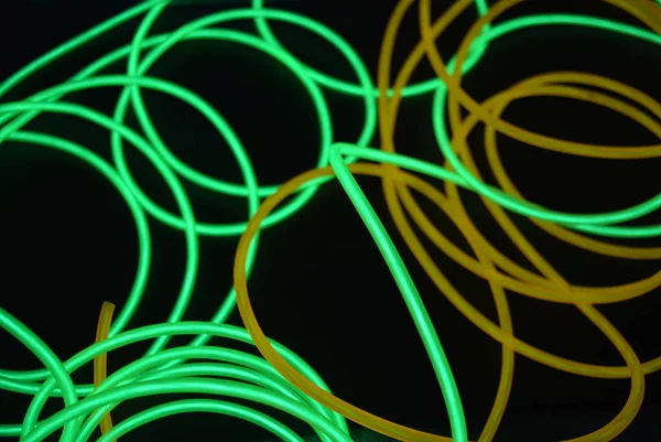 Bright luminous yellow and green, lime neon wires in different formats and layouts. An electroluminescent wire, a neon light guide, an ice tube are folded into different structures and shapes.