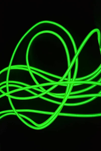 異なる形状および構造を有する有毒な緑色の発光電発光ワイヤー 黒い光沢のある表面に位置する石灰エレクトロルミネッセンス繊維 エルワイヤー 珍しい円のウェブ — ストック写真