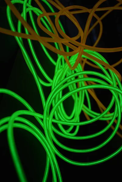 Bright luminous yellow and green, lime neon wires in different formats and layouts. An electroluminescent wire, a neon light guide, an ice tube are folded into different structures and shapes.