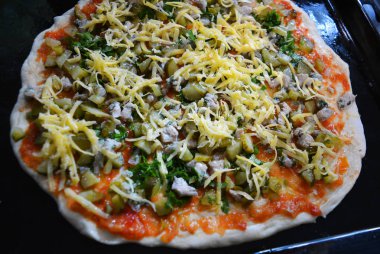 Ukrayna pizzası için nefis bir hazırlık tavuk göğsü, domates sosu, maydanoz, peynir ve siyah metal bir oyukta..
