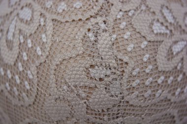 Güzel, çekici bej dantel, zarif ve alışılmadık kumaş beyaz bir arka planda yer almaktadır..