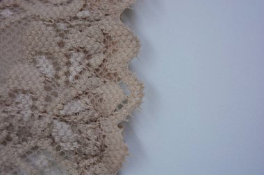 Güzel, çekici bej dantel, zarif ve alışılmadık kumaş beyaz bir arka planda yer almaktadır..