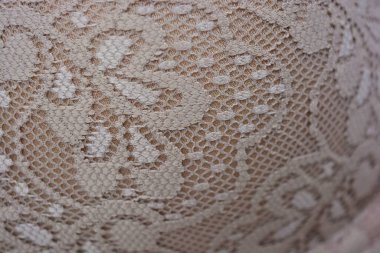 Güzel, çekici bej dantel, zarif ve alışılmadık kumaş beyaz bir arka planda yer almaktadır..