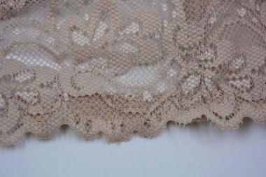 Güzel, çekici bej dantel, zarif ve alışılmadık kumaş beyaz bir arka planda yer almaktadır..