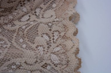 Güzel, çekici bej dantel, zarif ve alışılmadık kumaş beyaz bir arka planda yer almaktadır..