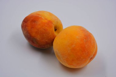 Beyaz bir tabakta iki büyük, olgun kırmızı-turuncu şeftali. Her gün için sağlıklı ve harika yemekler..