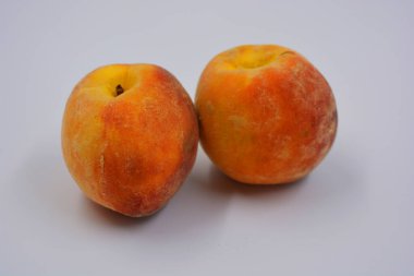 Beyaz bir tabakta iki büyük, olgun kırmızı-turuncu şeftali. Her gün için sağlıklı ve harika yemekler..