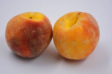 Beyaz bir tabakta iki büyük, olgun kırmızı-turuncu şeftali. Her gün için sağlıklı ve harika yemekler..