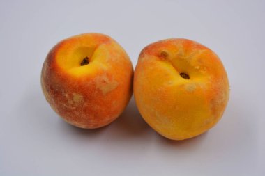 Beyaz bir tabakta iki büyük, olgun kırmızı-turuncu şeftali. Her gün için sağlıklı ve harika yemekler..