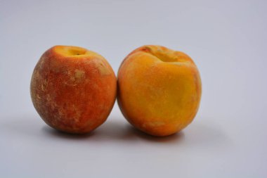 Beyaz bir tabakta iki büyük, olgun kırmızı-turuncu şeftali. Her gün için sağlıklı ve harika yemekler..