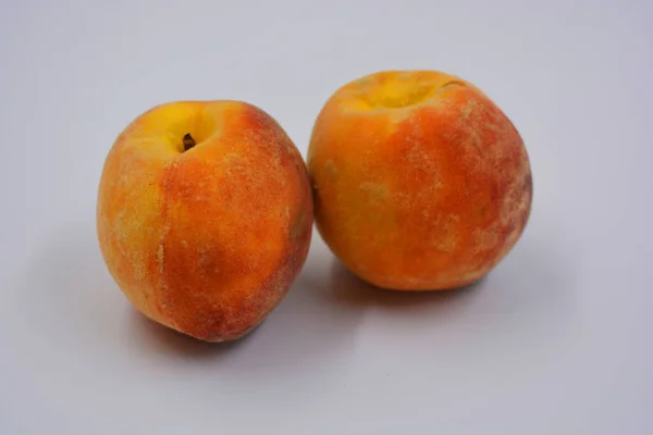 两个成熟的大红橙桃子放在一个白盘上 每日健康美味的食物 — 图库照片