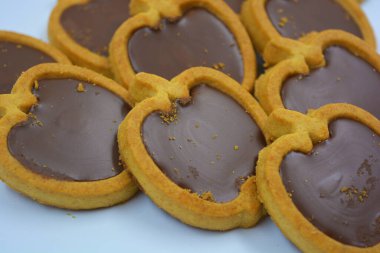 İçinde fındıklı, çikolatalı kurabiyeler olan taze, lezzetli çıtır kurabiyeler. Beyaz bir arka planda kahverengi dolgulu elma şekilli kurabiyeler.