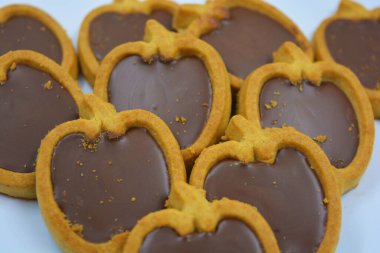 İçinde fındıklı, çikolatalı kurabiyeler olan taze, lezzetli çıtır kurabiyeler. Beyaz bir arka planda kahverengi dolgulu elma şekilli kurabiyeler.