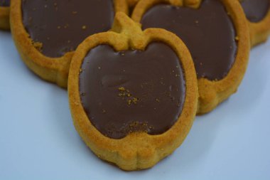 İçinde fındıklı, çikolatalı kurabiyeler olan taze, lezzetli çıtır kurabiyeler. Beyaz bir arka planda kahverengi dolgulu elma şekilli kurabiyeler.