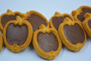 İçinde fındıklı, çikolatalı kurabiyeler olan taze, lezzetli çıtır kurabiyeler. Beyaz bir arka planda kahverengi dolgulu elma şekilli kurabiyeler.