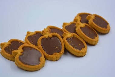 İçinde fındıklı, çikolatalı kurabiyeler olan taze, lezzetli çıtır kurabiyeler. Beyaz bir arka planda kahverengi dolgulu elma şekilli kurabiyeler.