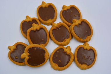 İçinde fındıklı, çikolatalı kurabiyeler olan taze, lezzetli çıtır kurabiyeler. Beyaz bir arka planda kahverengi dolgulu elma şekilli kurabiyeler.