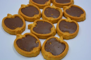 İçinde fındıklı, çikolatalı kurabiyeler olan taze, lezzetli çıtır kurabiyeler. Beyaz bir arka planda kahverengi dolgulu elma şekilli kurabiyeler.