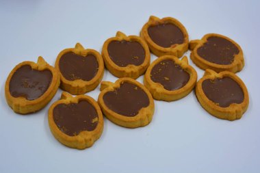 İçinde fındıklı, çikolatalı kurabiyeler olan taze, lezzetli çıtır kurabiyeler. Beyaz bir arka planda kahverengi dolgulu elma şekilli kurabiyeler.