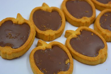 İçinde fındıklı, çikolatalı kurabiyeler olan taze, lezzetli çıtır kurabiyeler. Beyaz bir arka planda kahverengi dolgulu elma şekilli kurabiyeler.