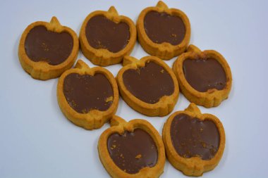 İçinde fındıklı, çikolatalı kurabiyeler olan taze, lezzetli çıtır kurabiyeler. Beyaz bir arka planda kahverengi dolgulu elma şekilli kurabiyeler.