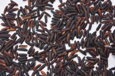 Beyaz bir tabağa serpiştirilmiş, uzun, cilalanmamış, kullanışlı siyah pirinç. Sağlıklı yiyecekler, sağlıklı mısır gevrekleri. Her gün için doğal pirinç..