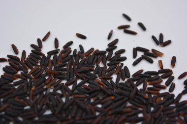 Beyaz bir tabağa serpiştirilmiş, uzun, cilalanmamış, kullanışlı siyah pirinç. Sağlıklı yiyecekler, sağlıklı mısır gevrekleri. Her gün için doğal pirinç..