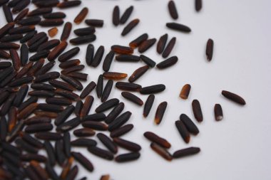 Beyaz bir tabağa serpiştirilmiş, uzun, cilalanmamış, kullanışlı siyah pirinç. Sağlıklı yiyecekler, sağlıklı mısır gevrekleri. Her gün için doğal pirinç..