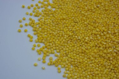 Çok sağlıklı ve kullanışlı homurtular, beyaz bir arka plana saçılmış sarı darılar. Bu mısır gevreğindeki yulaf lapası vücuttaki toksinleri temizler..