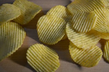 Patates kızartması, kabartma, ekşi kremalı patates cipsi, yeşillikler, ahşap bir tahtanın üzerindeki cilt..