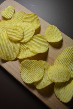 Patates kızartması, kabartma, ekşi kremalı patates cipsi, yeşillikler, ahşap bir tahtanın üzerindeki cilt..