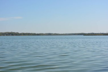 Güzel, parlak doğa, Ukrayna, Samara Nehri yakınlarındaki manzara. Ağaçları ve güzel yeni evleri olan yeşil bir bankanın arka planında küçük dalgalarla dolu derin mavi bir nehir..