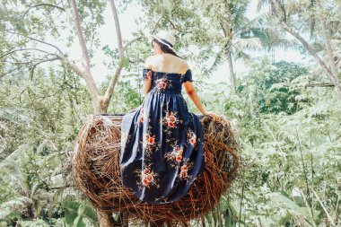 Güzel Asyalı kadın saman yuvasında oturuyor, Ubud, Bali.