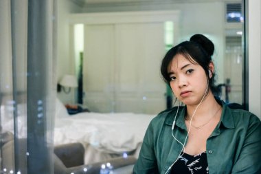 Genç ve güzel Asyalı kadın pencerenin yanında oturuyor.