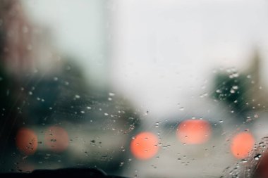 Kırmızı bokeh ışığıyla bulanık yağmurlu pencere